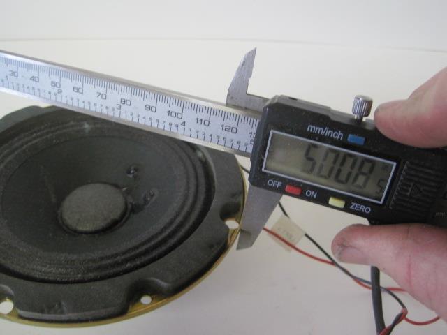 a person is holding a caliper and measuring the width of a speaker
